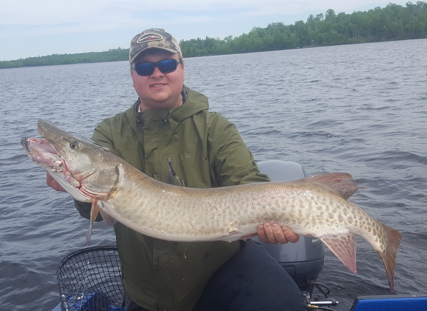 Gentleman showing of the fish he caught while on a northland muskie adventure