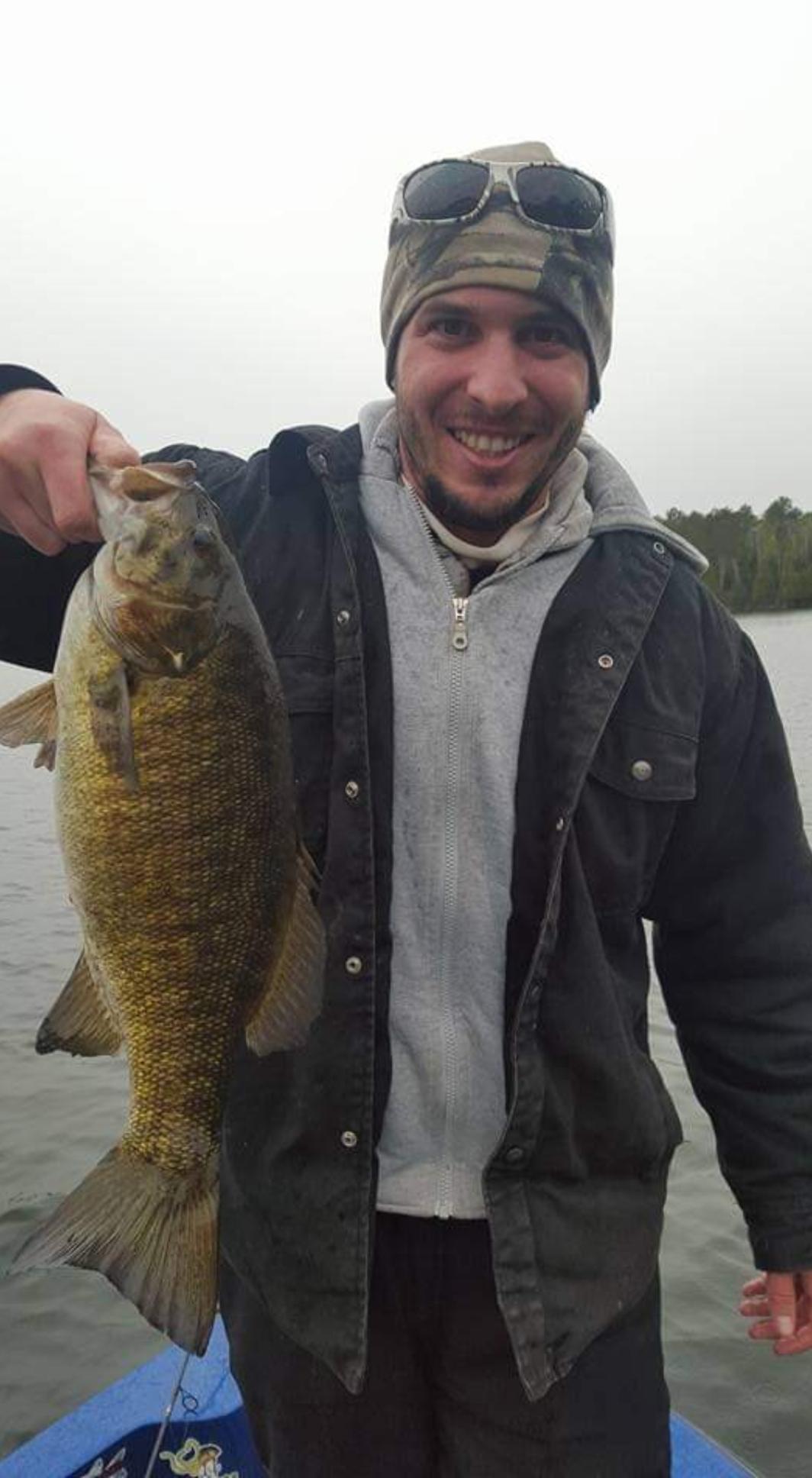 Guy holding up the fish that he caught on the lake